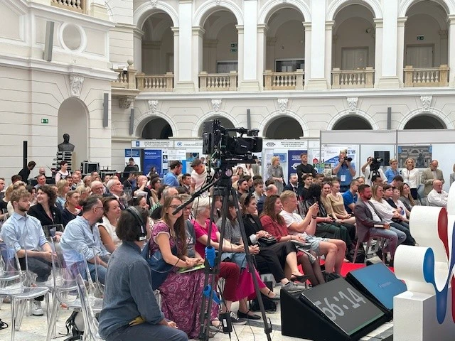 Tłum ludzi przy zabytkowym budynku ze zdobioną fasadą