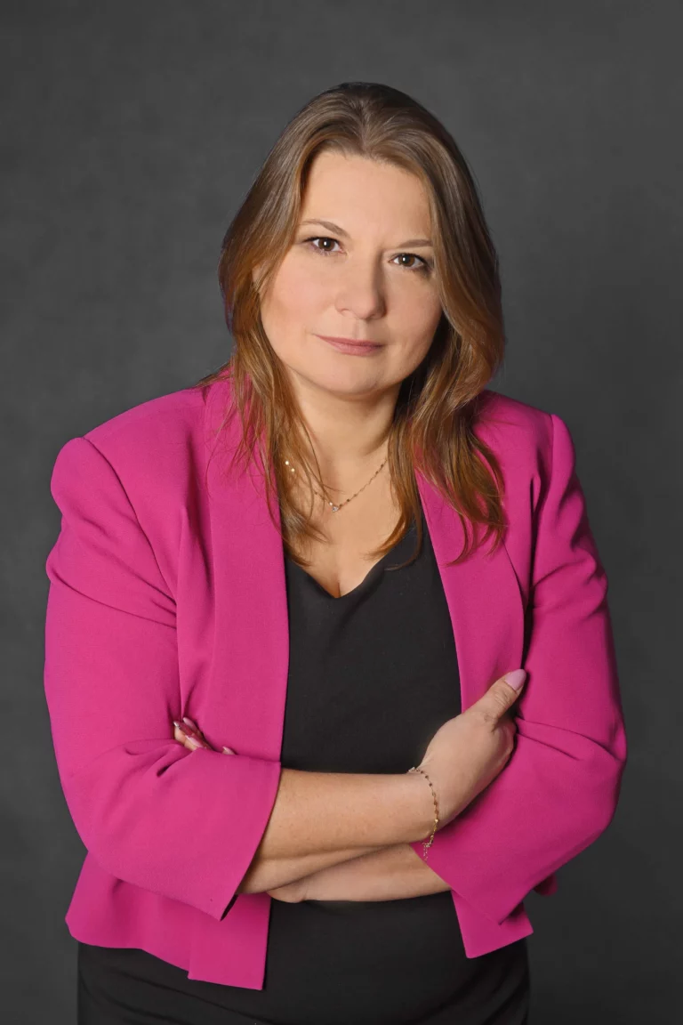 Elegancko ubrana kobieta stoi trzymając skrzyżowane ręce