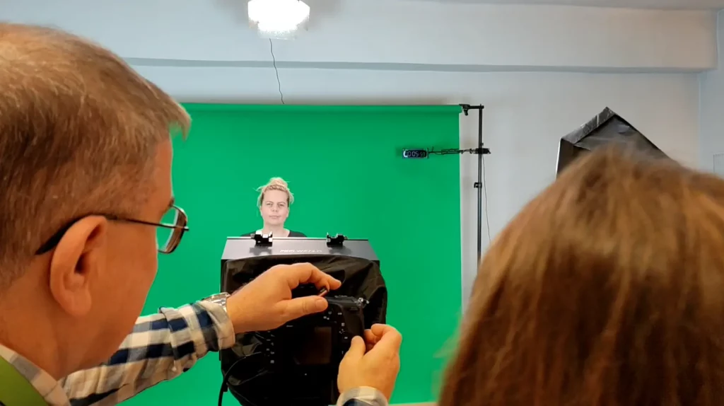 Dwie osoby przy urządzeniu, a trzecia na siedzi na wprost nich