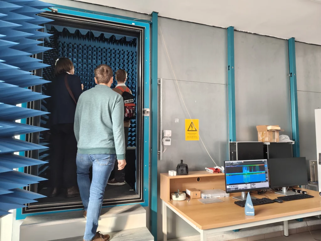 Grupa osób wchodzi po schodkach do małego pomieszczenia z płytkami na ścianach