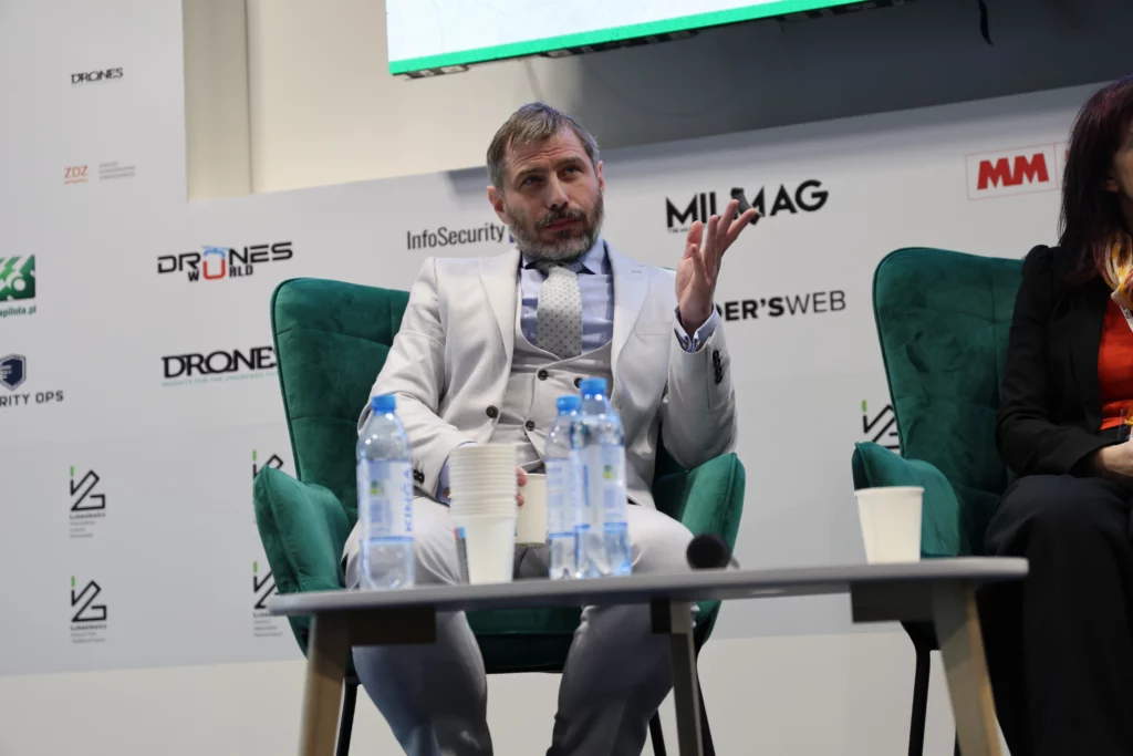 Man sitting on stage speaking into a microphone.