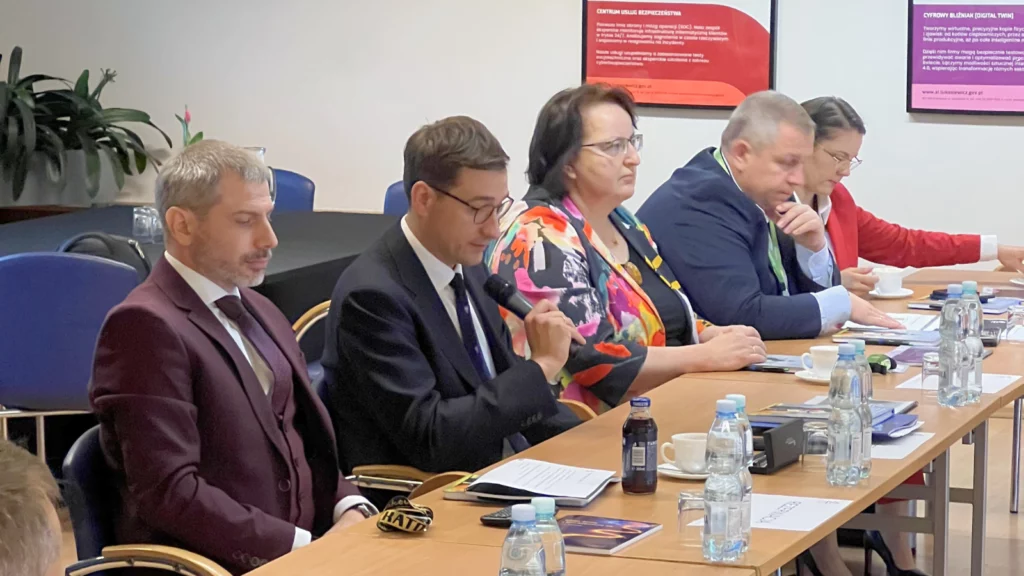 Grupa osób siedząca przy stole na oficjalnym spotkaniu