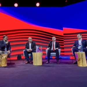 Grupa mężczyzn w garniturach siedzi na scenie