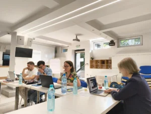 Grupa osob na sali konferencyjnej przy biurkach